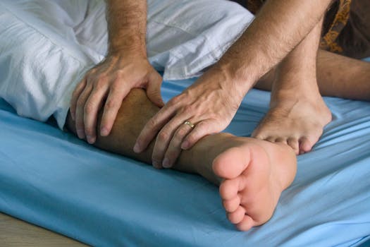 Close-up of Health and Fitness Team providing hands-on physical therapy in Woodbridge NJ, working on a patient's lower leg on a blue treatment table.