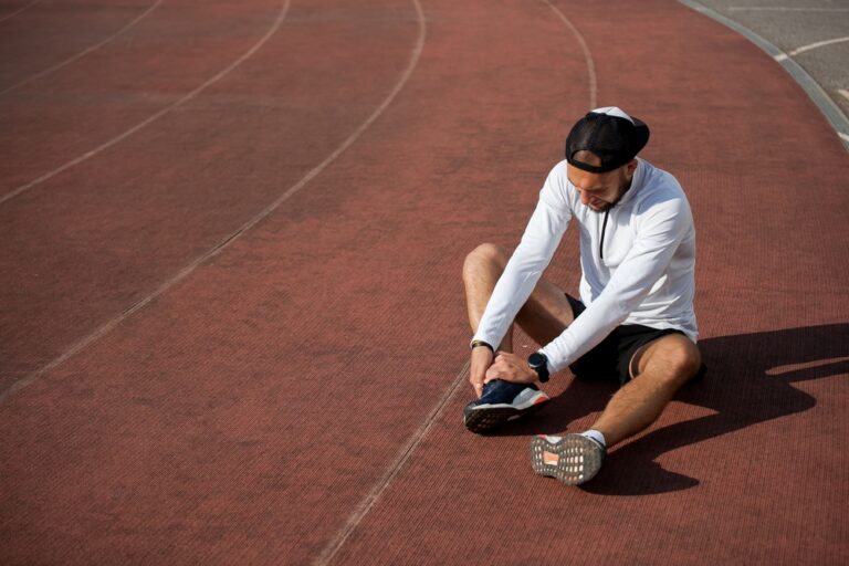image of a man on a track field suffering from an injury in his ankle